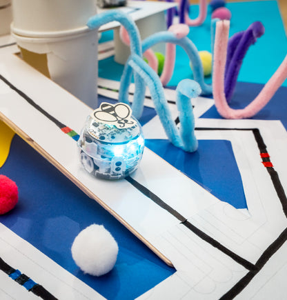 Ozobot coding robot navigating a colorful student-created design mat with pathways and three-dimensional structures during a hands-on STEM activity.