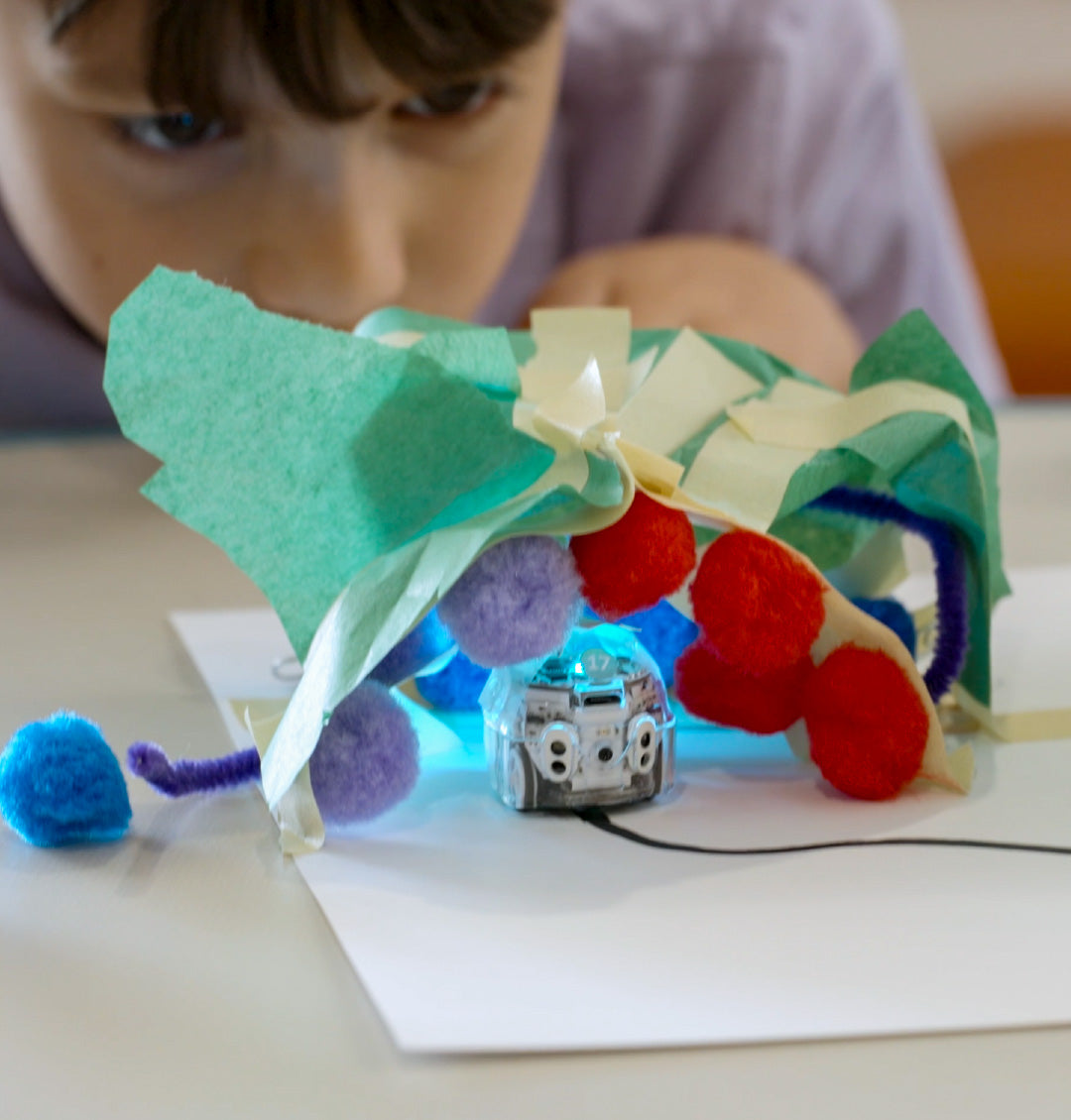 Elementary school student working on a colorful hands-on design project with an Ozobot coding robot, combining creativity, engineering, and robotics.